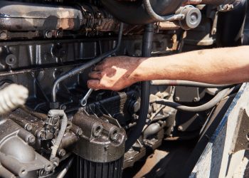 Combine machine service, mechanic repairing motor outdoors.